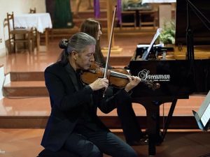 Violinista dell'Experience Trio accanto a un pianoforte a coda Saccuman